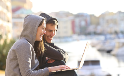 Young men and women chatting while looking at a laptop